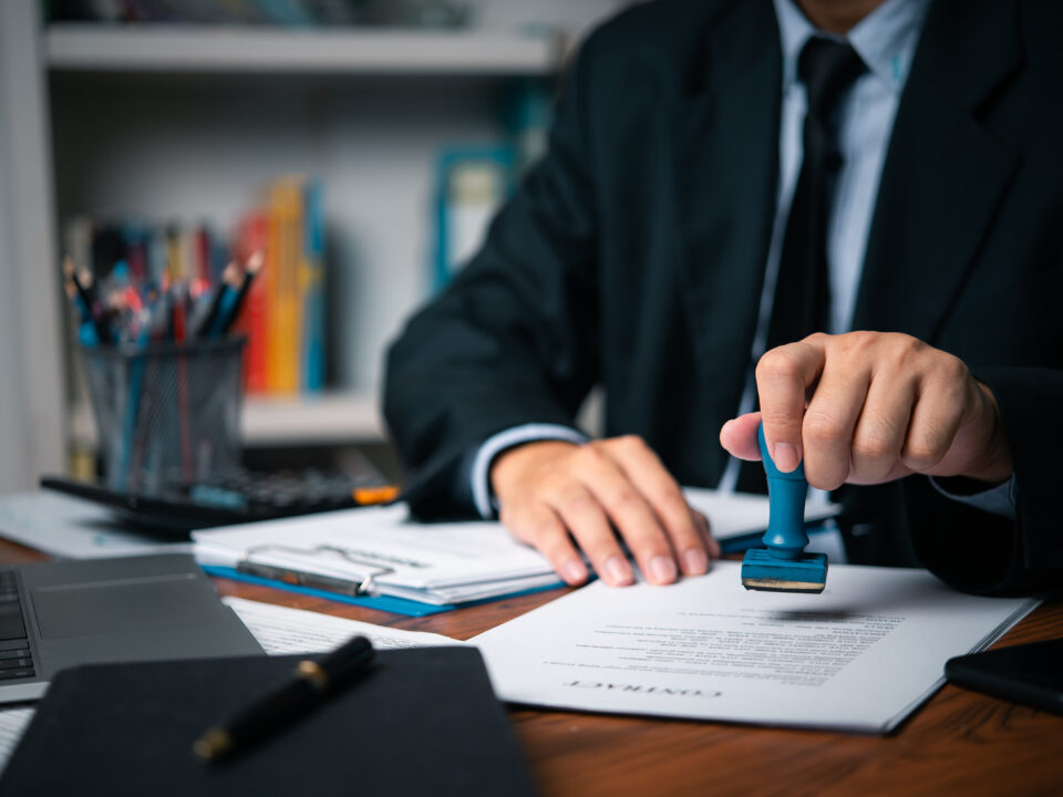 Hand man stamping documents notary public in office . Businessperson stamping approval of work finance banking or investment marketing documents on desk.