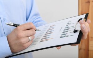 Hand zeigt mit Stift auf Klemmbrett mit Diagrammen, steuerliche Folgen oder Betriebsaufspaltung werden leicht erklärt.